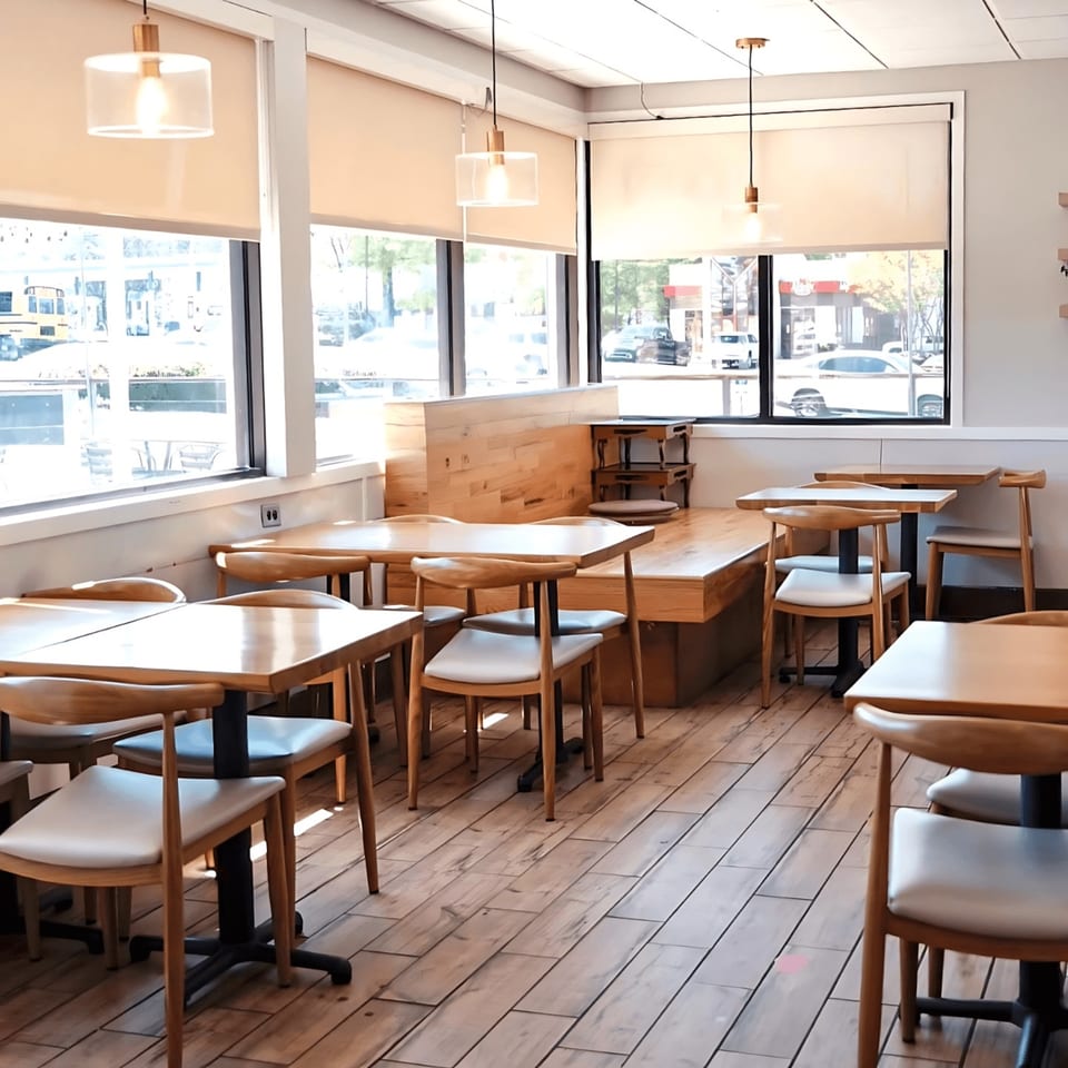 Cafe Mixx dining area with light wood tables, chairs, and flooring, illuminated by natural light.