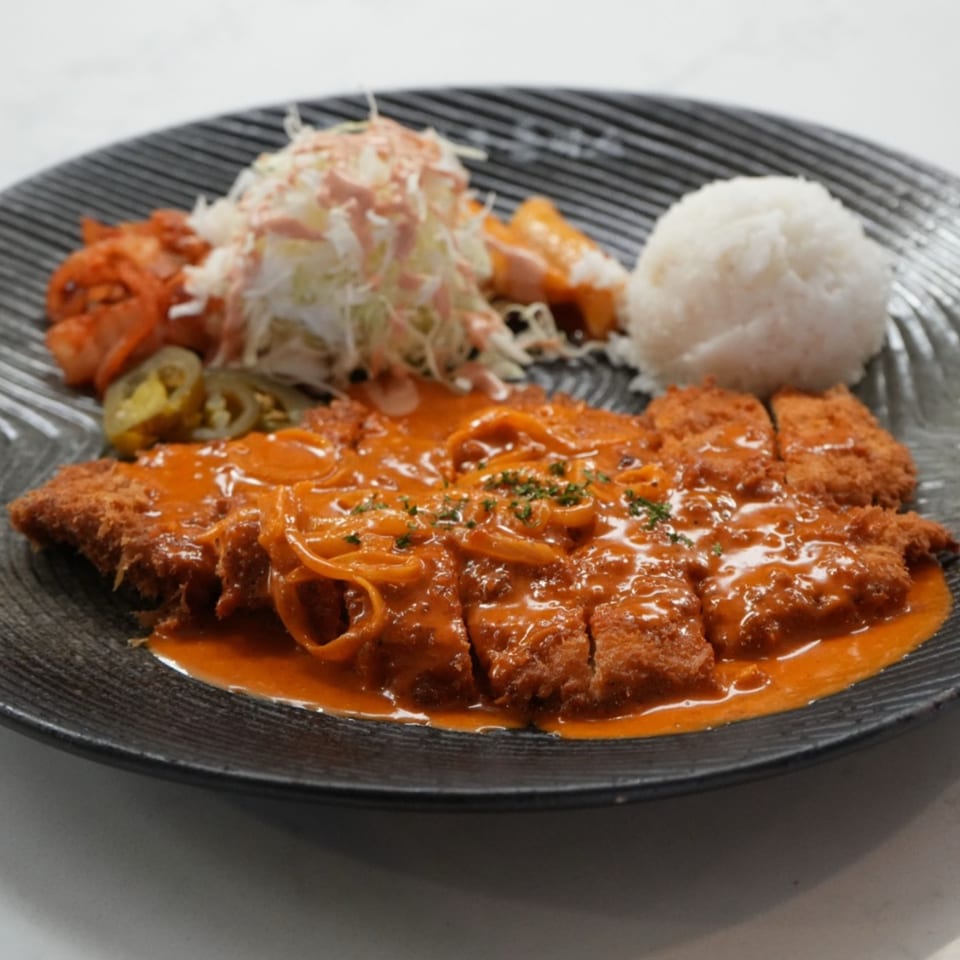 Cafe Mixx's pork cutlet with red sauce, rice, coleslaw, kimchi, and pickled jalapeños.
